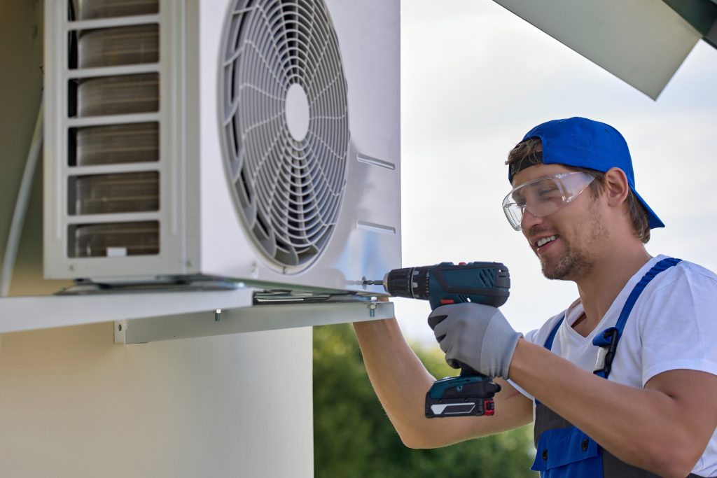 HVAC technician performing preventive maintenance on an outdoor air conditioning unit in Savannah before summer.
